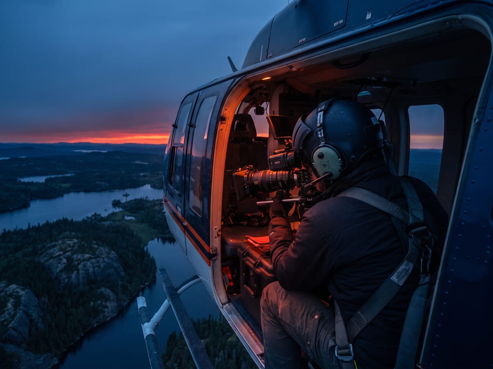 Camera operator shooting from the open door of a helicopter in flight